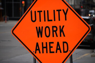 Utility Work Ahead orange construction street sign in urban city
