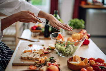 The professional master chef prepares a bowl of various types of fruit and vegetable salad with great passion and enthusiasm. Expertly mix all the ingredients and materials with care and precision.