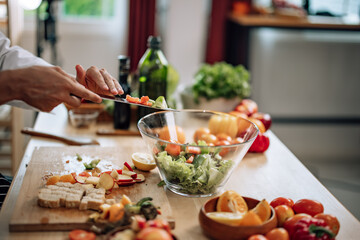 The professional master chef prepares a bowl of various types of fruit and vegetable salad with great passion and enthusiasm. Expertly mix all the ingredients and materials with care and precision.
