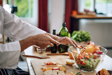 The professional master chef prepares a bowl of various types of fruit and vegetable salad with great passion and enthusiasm. Expertly mix all the ingredients and materials with care and precision.