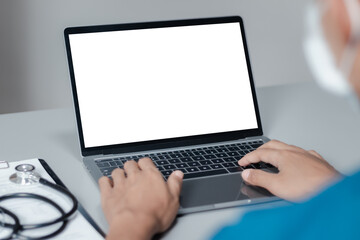 Mockup of doctor using and typing on laptop with blank white desktop screen.