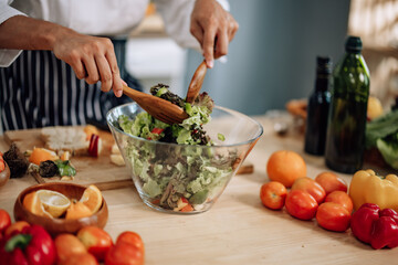 The professional master chef prepares a bowl of various types of fruit and vegetable salad with great passion and enthusiasm. Expertly mix all the ingredients and materials with care and precision.