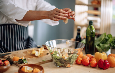 The professional master chef prepares a bowl of various types of fruit and vegetable salad with great passion and enthusiasm. Expertly mix all the ingredients and materials with care and precision.