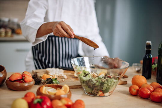 The professional master chef prepares a bowl of various types of fruit and vegetable salad with great passion and enthusiasm. Expertly mix all the ingredients and materials with care and precision.
