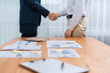 Two businesspeople shake hand after signing contract document to merge their partnerships in...