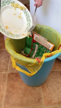 Throw leftover food off the plate into the trash. Throw away pasta left over from dinner