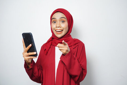 Asian Muslim businesswoman in red casual holding a smartphone isolated by a white background