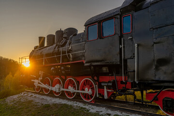 Fototapeta na wymiar Old steam locomotive at sunset in the mountains. Retro style.
