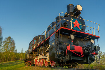 Old steam locomotive on a background of blue sky and green grass