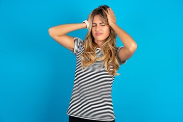 Fototapeta premium young beautiful woman wearing striped t-shirt suffering from strong headache desperate and stressed because of overwork. Depression and pain concept.