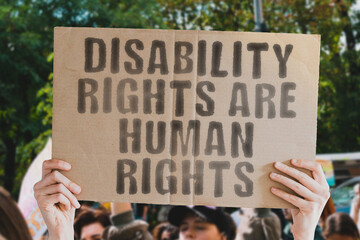 A powerful image of a man’s hand holding a banner with the text ‘Disability rights are human...