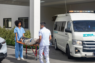 Two paramedic rescuers helping a patient after having an accident. African nurse works with her colleague using stretcher to move a patient to ambulance van. © Ron