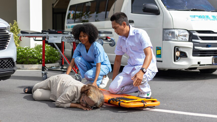 Two paramedic rescuers helping a patient after having an accident. African nurse works with her...