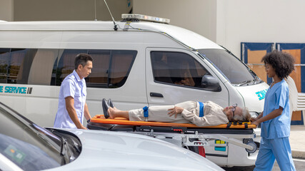 Two paramedic rescuers helping a patient after having an accident. African nurse works with her colleague using stretcher to move a patient to ambulance van.