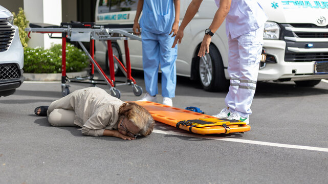 Two paramedic rescuers helping a patient after having an accident. African nurse works with her colleague using stretcher to move a patient to ambulance van.