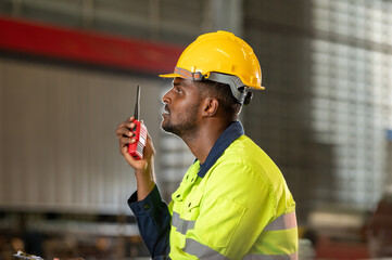 male maintenance engineer in uniform helmet safety talk by walki talkie and inspection check control heavy machine in industrial factory. technician worker use radio check for repair factory machine