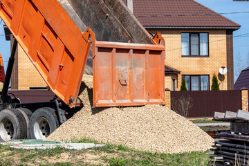 Truck pours rubble on the ground.