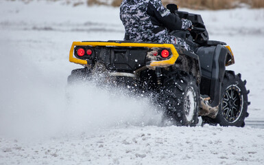 Quad bike rides on white snow in winter. Sport