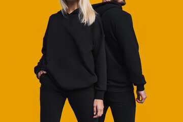 Woman stands in black no logo hoodie with bearded man behind her. Clothes branding mockup. Design...