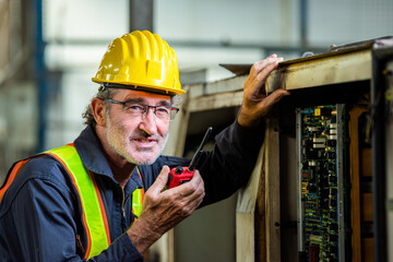 male maintenance engineer in uniform helmet safety talk by walki talkie and inspection check control heavy machine in industrial factory. technician worker use radio check for repair factory machine