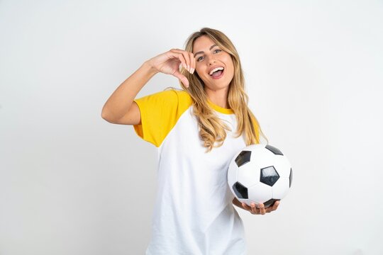 Serious Young beautiful woman wearing football T-shirt over white background keeps hands crossed stands in thoughtful pose concentrated somewhere