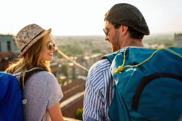 Portrait of young tourists couple with backpacks sightseeing city together on summer vacation.