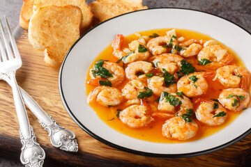 Gambas al ajillo or garlic shrimp is a traditional Gambas al ajillo or garlic shrimp is a traditional Spanish tapas made by combining fresh shrimp with an ajillo sauce on the wooden board. Horizontal