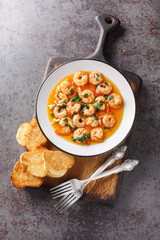 Spanish Garlic Shrimp Gambas al Ajillo closeup on the plate served with toasts on the wooden board....