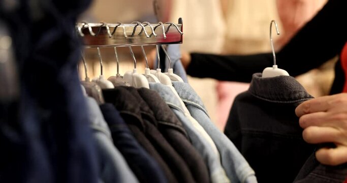 Woman hands choose children clothes in store. Selection of things for child in shopping center