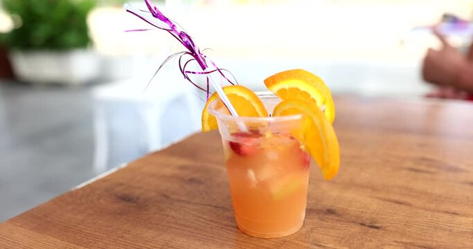 Orange cocktail with straw and slice of orange and strawberries on sea beach. Summer delicious cold vitamin cocktail