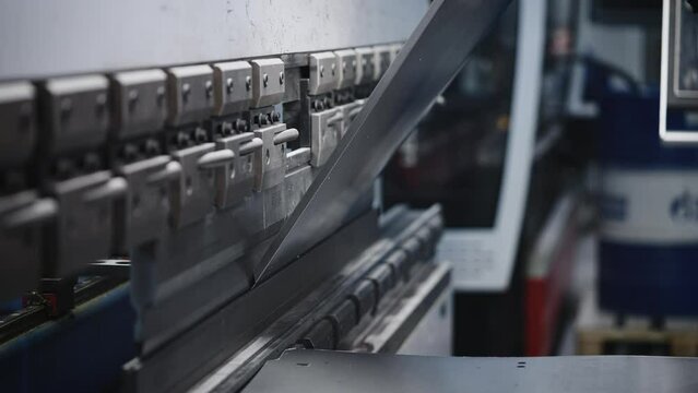 The process of bending steel sheet in production. A worker makes parts with a machine tool and a press
