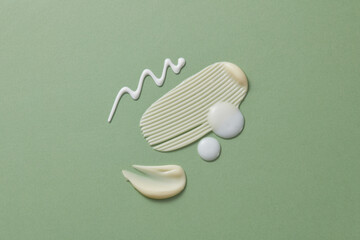 Smears of cosmetic cream texture and some drops of cream on pastel green background. The texture of a cosmetic skin care product