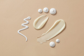 Cosmetic textures of moisturizers, lotions, sunscreens and body creams lie flat on a dark beige background. Product and promotion concept for advertising