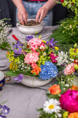 Gesteck aus frischen Blumen in einer Schale aus Keramik, Pfingstrose, Kamille, Margeriten, Clematis und Schleierkraut als Dekoration für den Tisch, Blumengesteck 