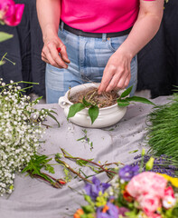 Florist arrangiert bunte Blumen in einem Gefäß aus Keramik, Blumengesteck mit frischen Blumen, 