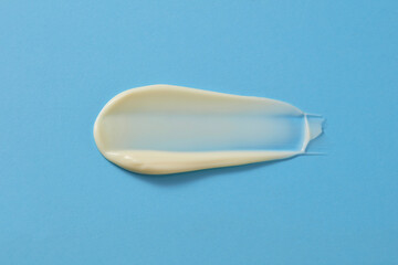 Moisturizing cream applied to face or body with thick milky texture isolated on a blue background. View from above for advertising cosmetic product with copy space