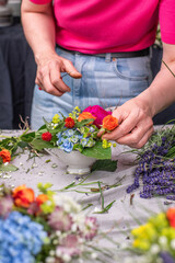 Florist arrangiert bunte Blumen in einem Gefäß aus Keramik, Blumengesteck mit frischen Blumen, 