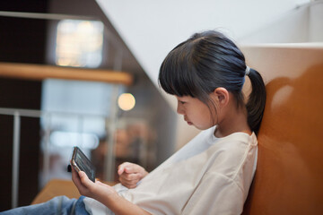 室内でスマホを見ている小学生の女の子の様子