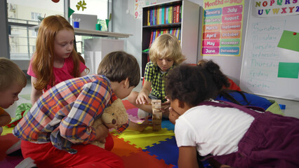 Diverse kids play with wooden blocks on warm floor at kindergarten