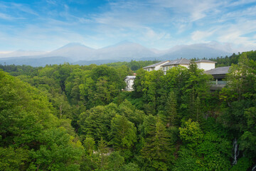 Fototapeta premium 青空と緑の森と山の中にある建物