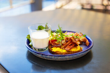 Very bright and healthy breakfast on a plate - bacon, egg, salad, tomato, cheese, a glass of yogurt.