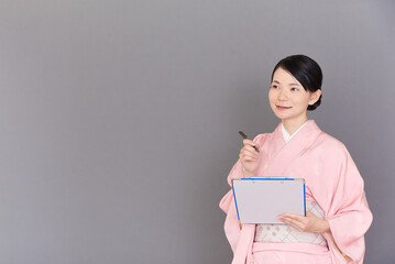 Obraz premium メモを書く着物を着た女性