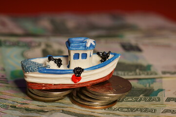 A toy boat with coins and money on the table. Finance and economics. Tourism and recreation.