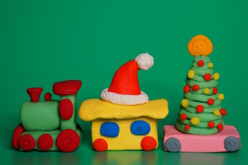 A toy train with a Christmas tree and a Santa Claus hat. Christmas decorations. Green background.