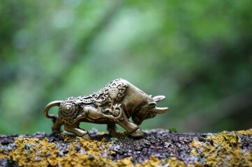 A statuette of a metal bull on a green background.