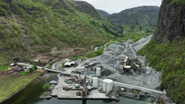 Sand, rock and gravel processing plant in Eikefet Norway. Car drives on Highway E39 in middle - Aerial