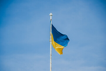 Ukrainian national flag is blowing in the wind with a deep blue sky behind