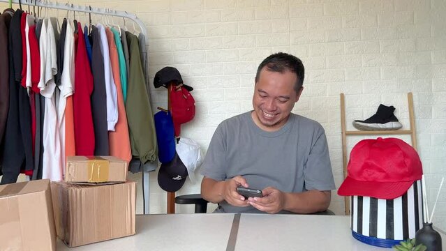 Young adult people asia man happy smile looking at good news on phone joy getting order at home office. Smart SME money lending for online shop store.