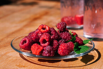 Red raspberry in a plate on the kitchen table, summer food. Background of fruity ripe berries