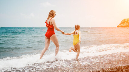 Happy loving family mother and daughter having fun together on the beach. Mum playing with her kid in holiday vacation next to the ocean - Family lifestyle and love concept